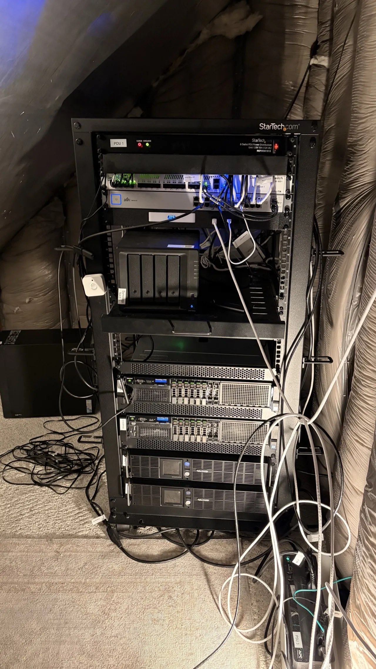Full 25U server rack in the attic showing both Dell R730 servers, MikroTik and UniFi networking, Synology NAS, and dual UPS units