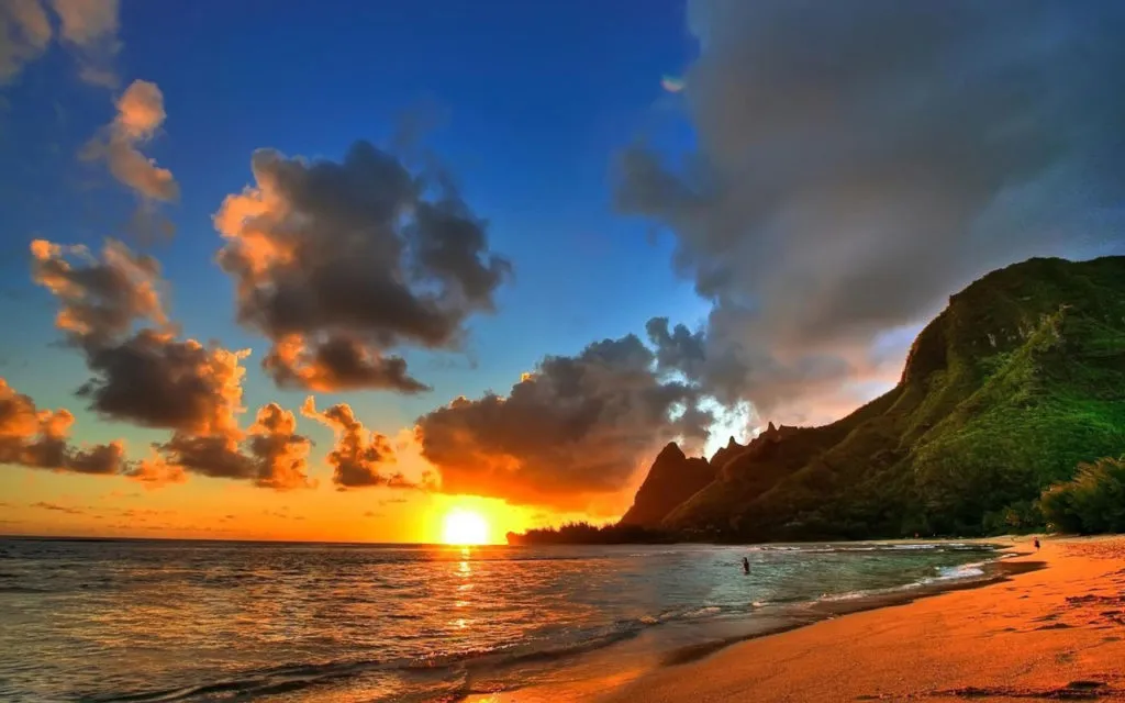 Golden sunset over Hawaiian beach with mountain silhouette