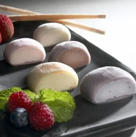 Assorted mochi ice cream on a dark plate with fresh berries