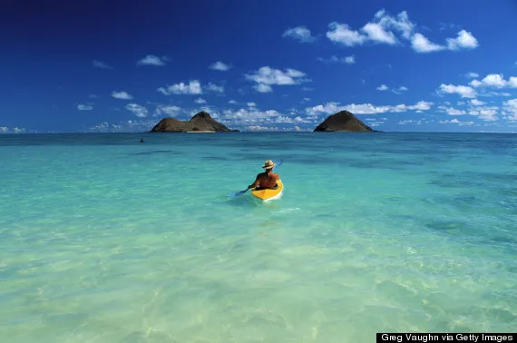 Hawaii, Oahu, Back view of a man wearing a hat on kayak heading to Mokulua Islands, blue skies