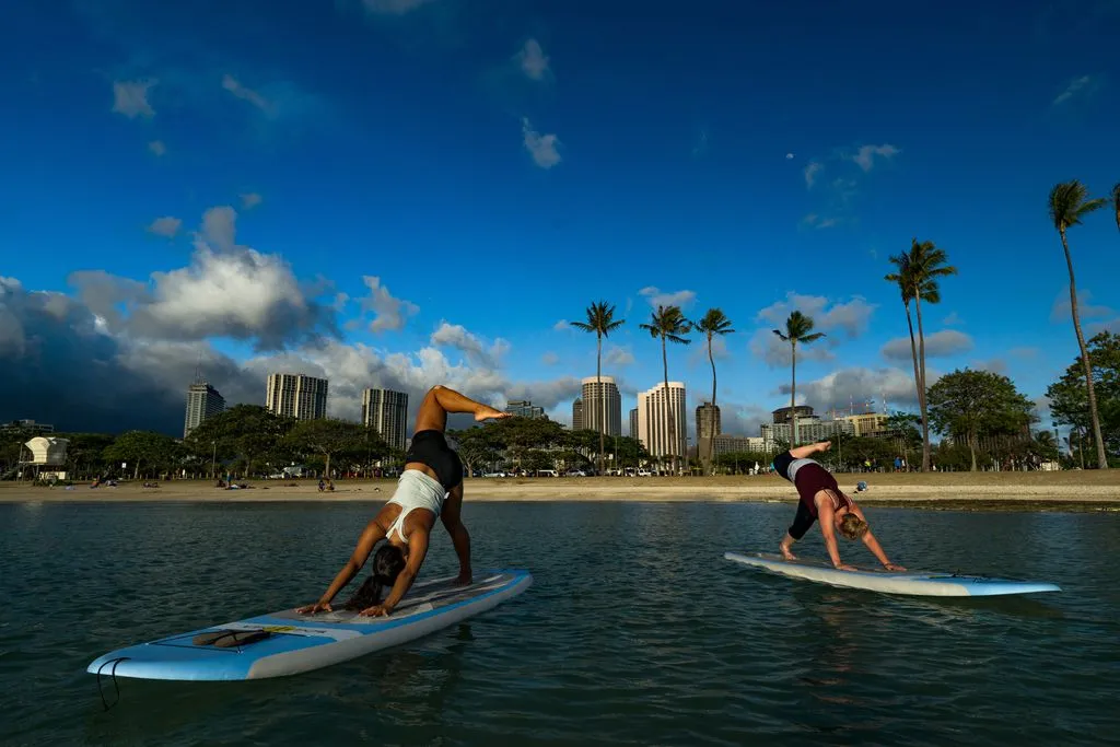 Two people doing yoga on paddleboards at Ala Moana Beach