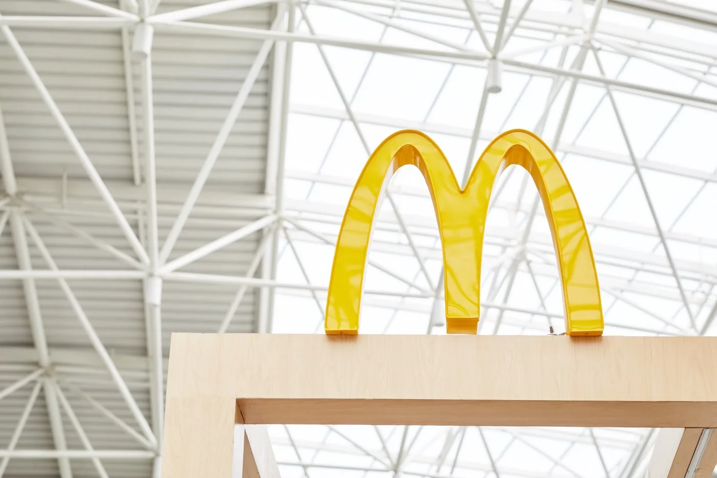 McDonald's golden arches sign under a glass atrium roof