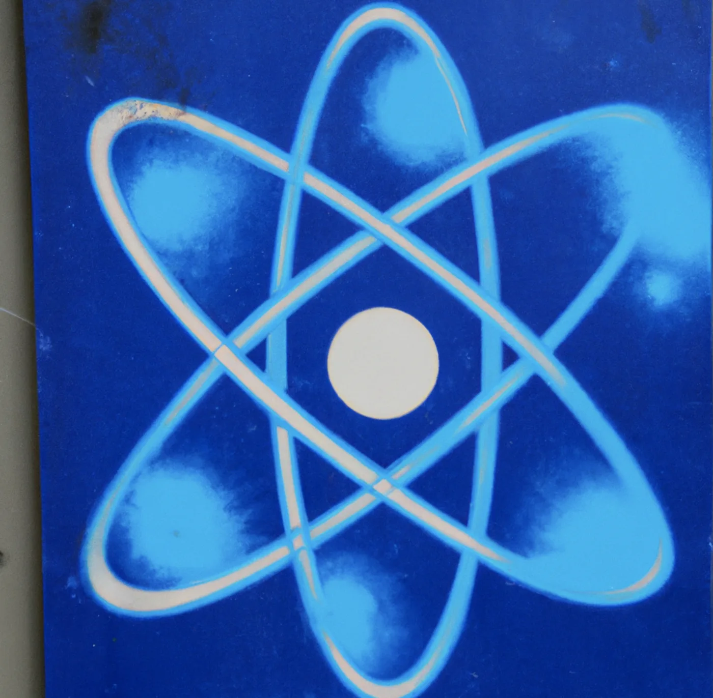 Painted atom symbol in light blue on a dark blue wall